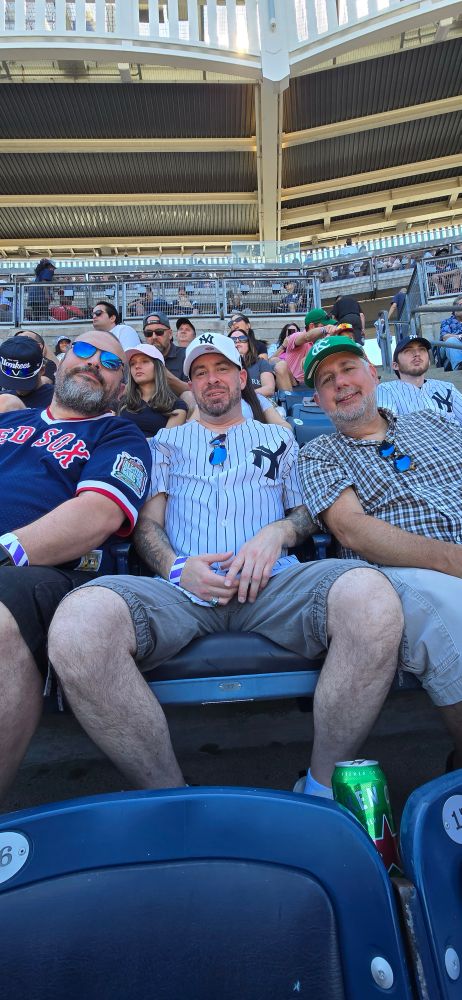 Three people watching a game at Yankee Stadium.