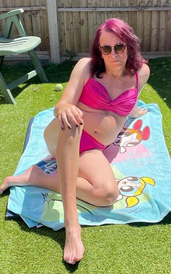 A trans woman sunbathing in a pink bikini 