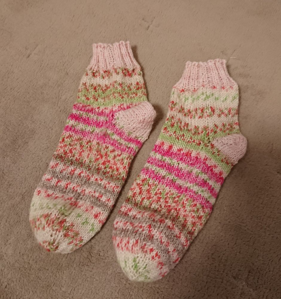 段染めの毛糸で編んだ靴下。主な色として緑、白、茶色、蛍光ピンクなど。かかとと履き口は毛糸を変えて薄いピンクで揃えた。