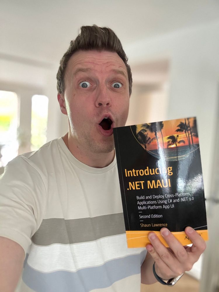 Gerald holding up the book Introducing .NET MAUI while making a silly face. 