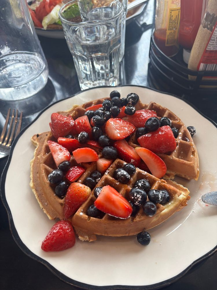 Big Belgian waffle covered in strawberries and blueberries. 