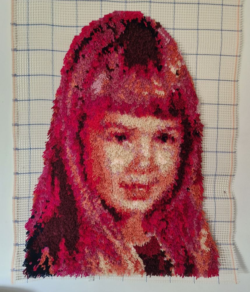 Artwork that is of a young girls face, in shades and hues of pinks and reds.