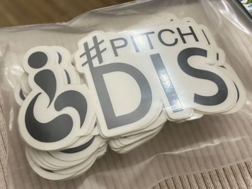 Stack of stickers with the #PitchDis logo in black.