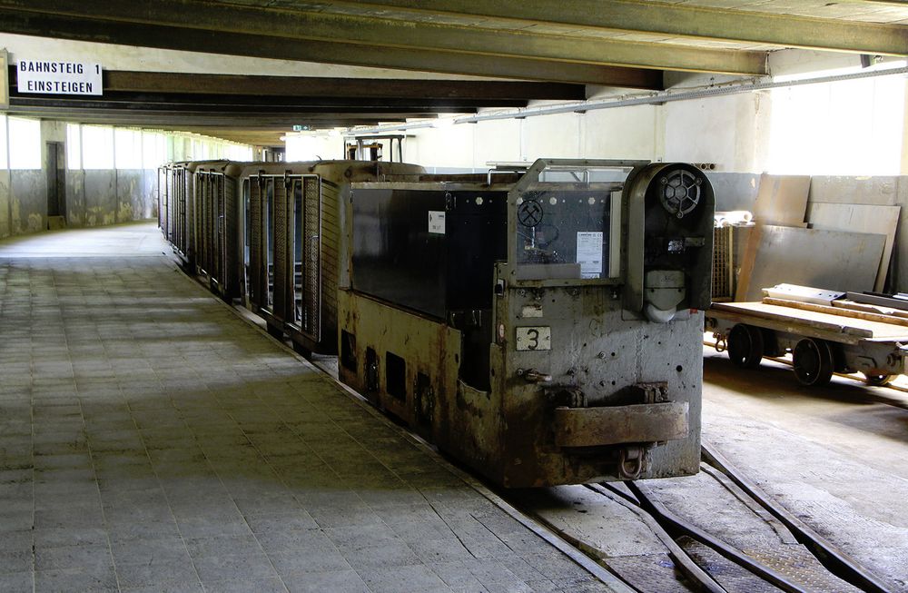 Photo of an empty mining train in the above-ground station, once all passengers have left. It consists of man cars, hauled by a 1950s battery locomotive.