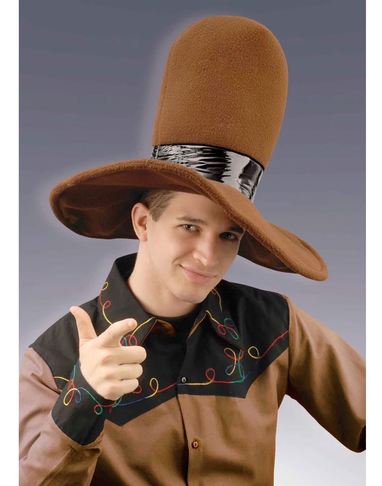 a man in an enormous brown felt hat. it looks kind of like a cowboy hat but with more of a jamiroquai vibe. he's wearing a cowboy type shirt and doing a finger gun at the camera. his expression is between a smirk and a grimace.