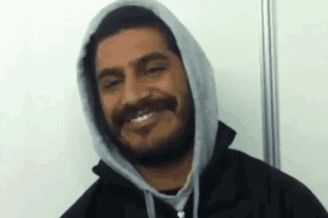 a man with a beard and mustache is wearing a hooded jacket and smiling .