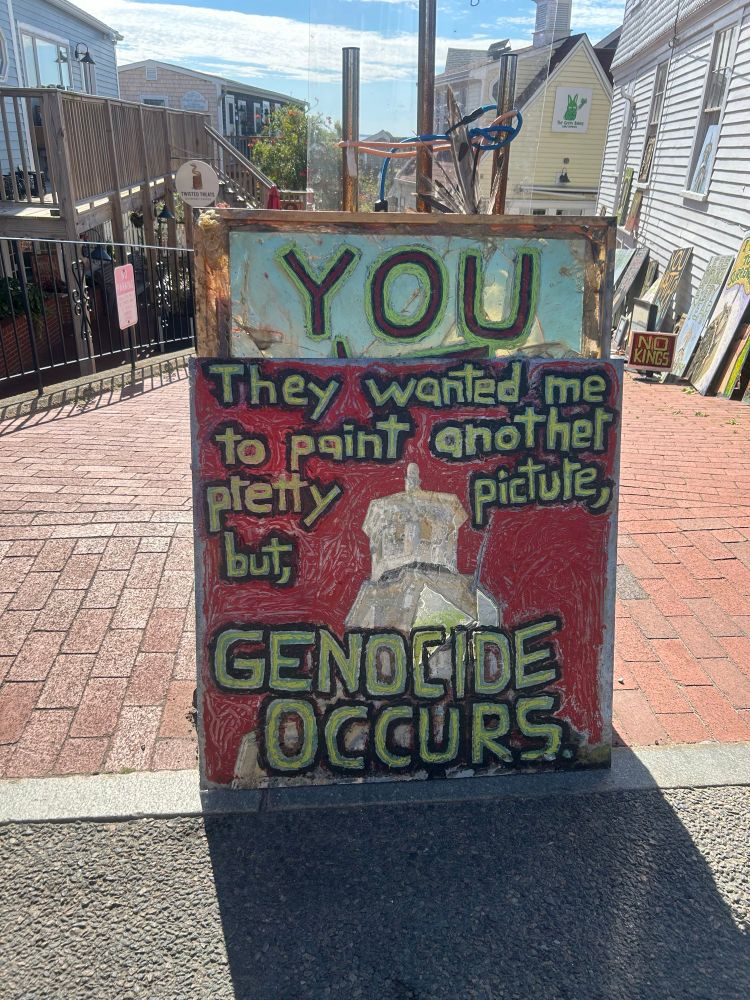 A painting that reads: They warlee me to paint another pretty picture but GENODCIDE OCCURS