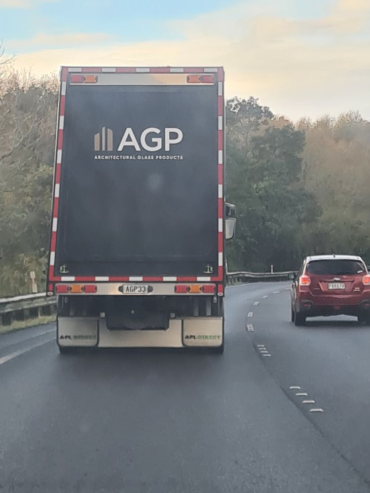 truck driving on a road which says 'agp' on the back
