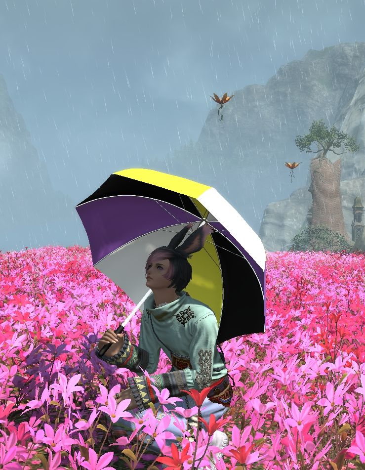 My WoL, Ziero, kneeling amidst flowers, looking up from under an umbrella with Non-binary flag colors. He wears a mint green shirt and jeans.