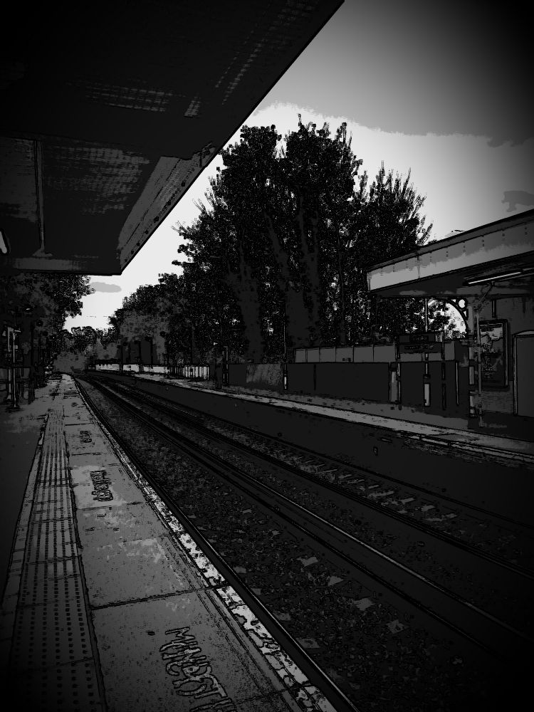B&W of Carshalton Station, empty rails stretching into the distance 