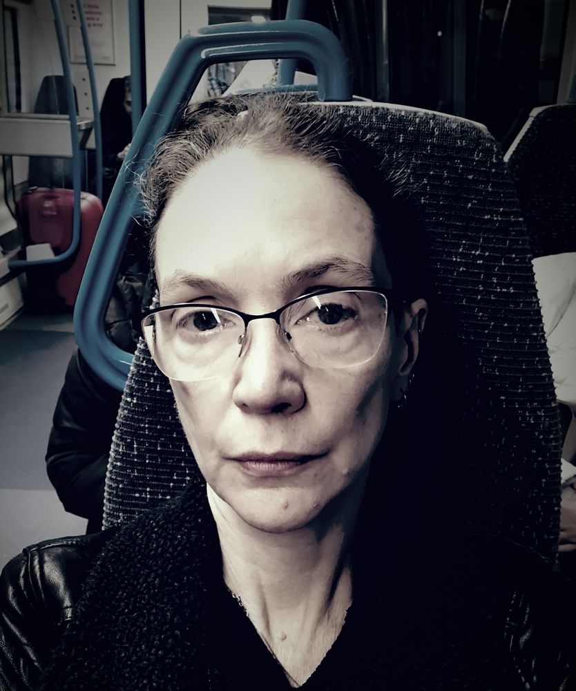 In a train seat, in varifocals and a slightly grotty leather jacket. 