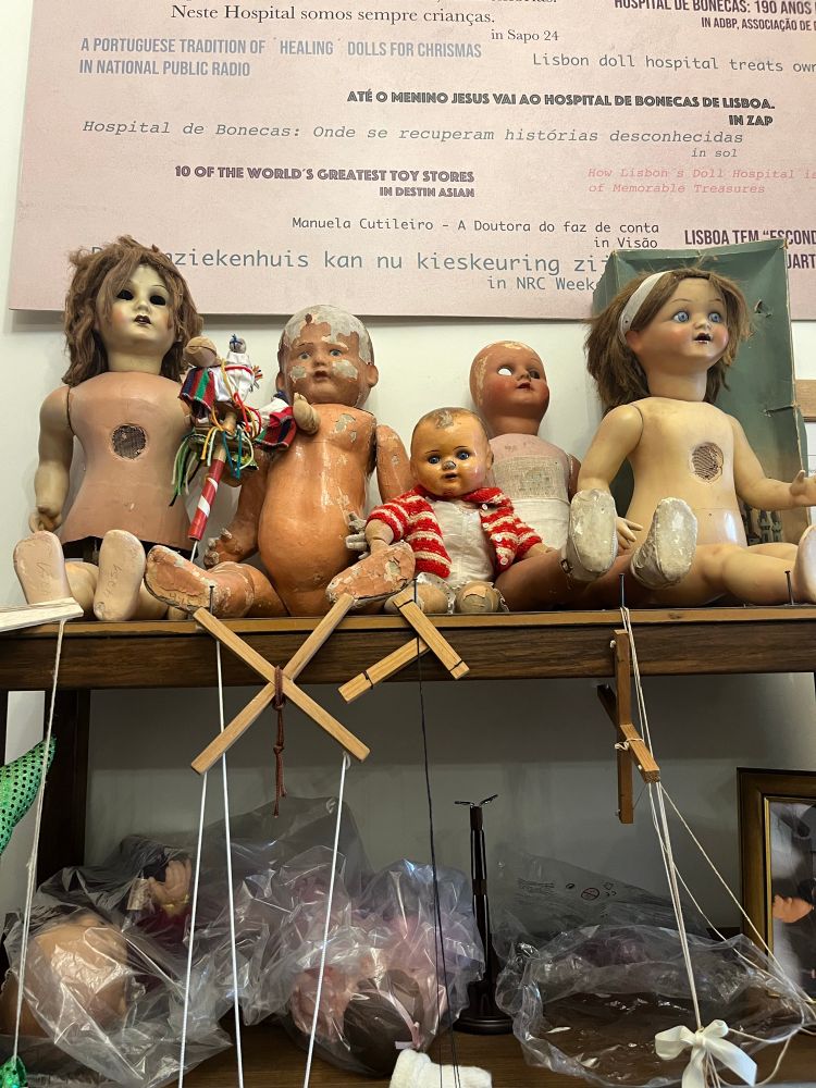 Old naked dolls on a shelf. Puppet strings and handles hang below 