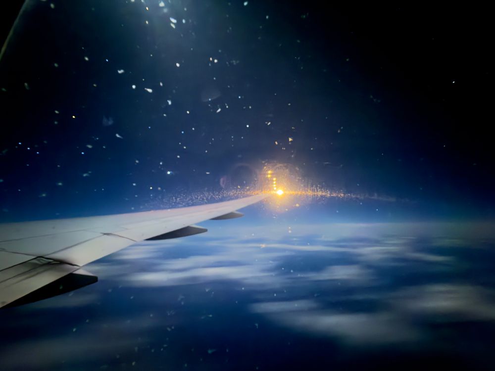 The wings of plane with passing clouds in the night