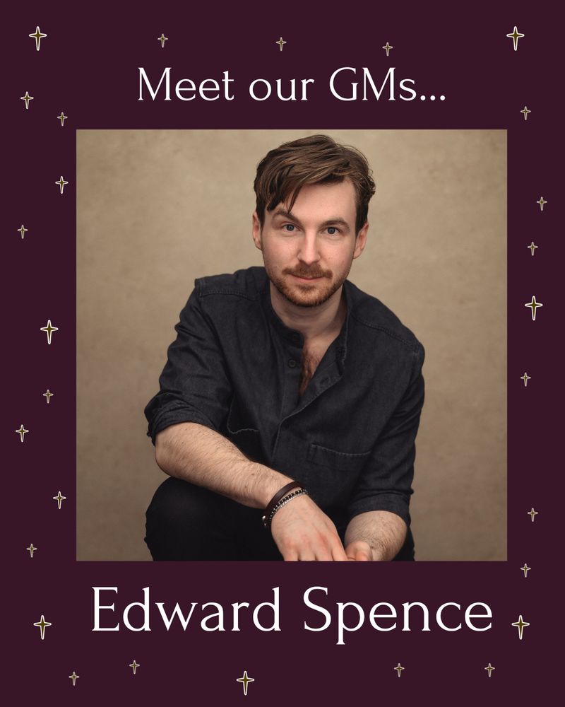 Edward (he/him) headshot wearing a dark shirt and black trousers with sleeves rolled up and a leather type bracelet. Sat on a stool in front of a light brown backdrop. 