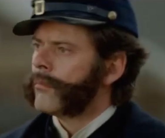 A screenshot of Alex Hyde White portraying Burnside, looking pensive.