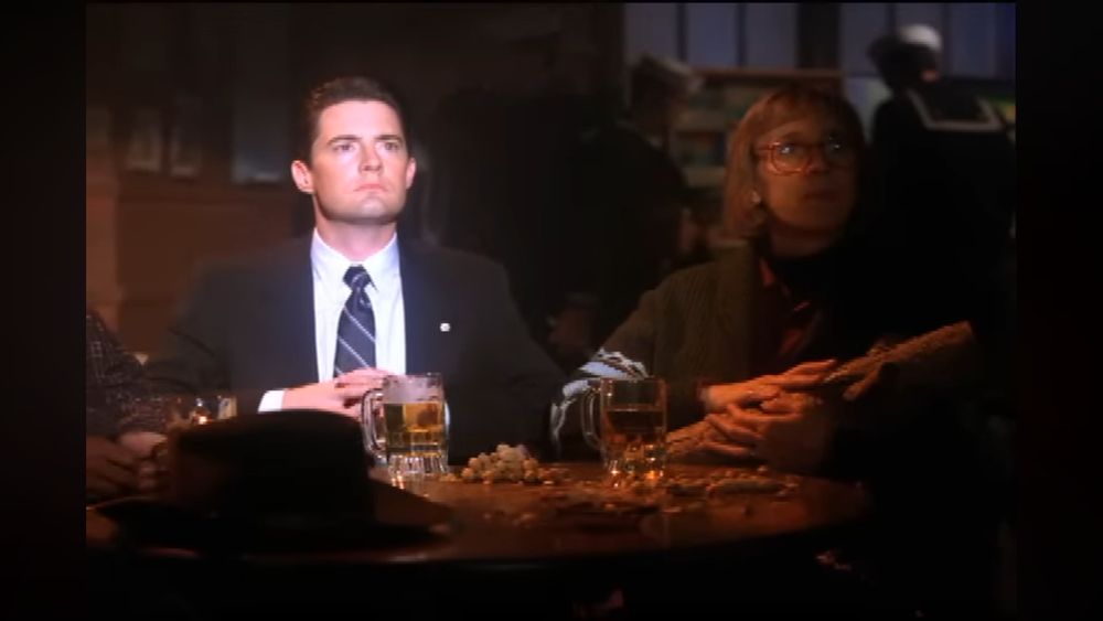 Agent Dale Cooper, glowing in a spotlight, reacts to a strange apparition on the stage