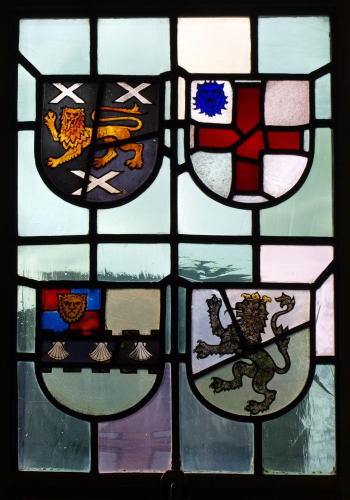 Stained glass window detail with four heraldic motifs