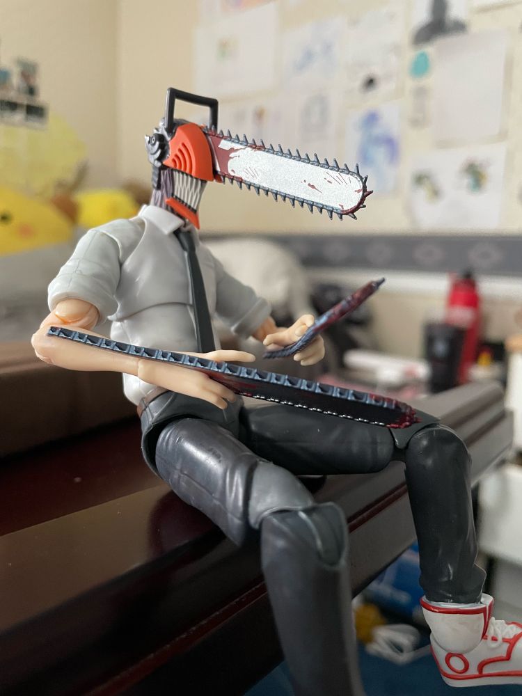 denji from chainsaw man sitting on the edge of my desk with his legs over the edge, looking melancholy and thoughtful