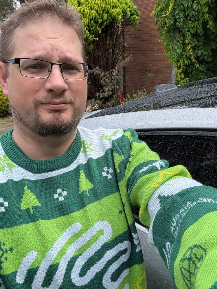 Myself ina hideous lime green, pine green and Christmas Aussie broadband themed sweater. 