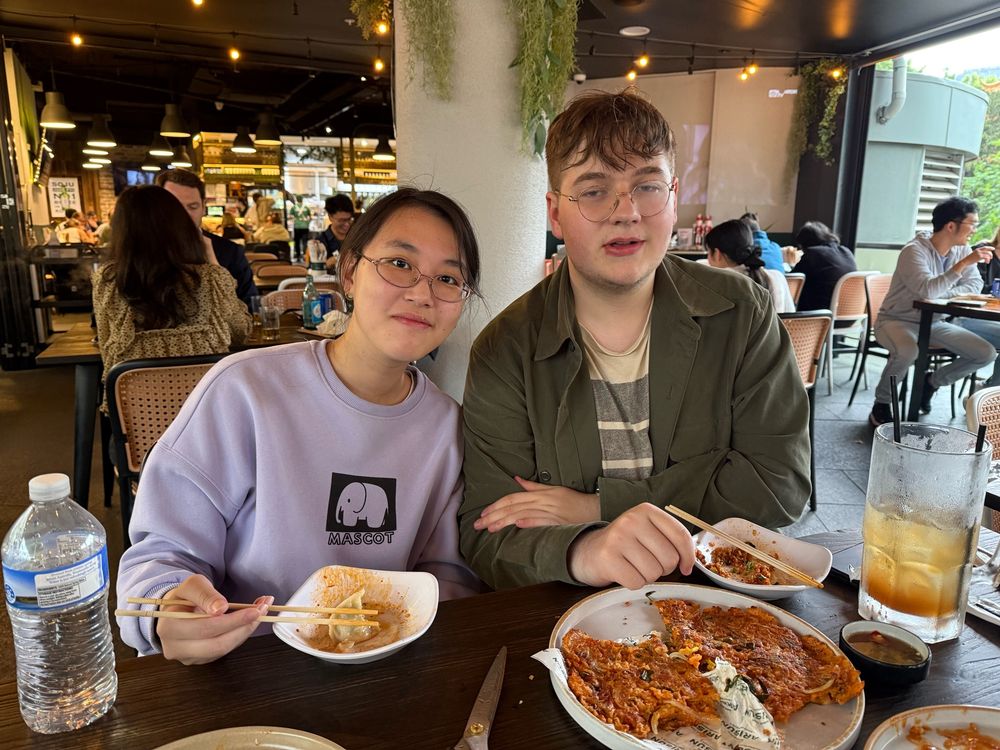 My son and his GF sitting at a table eating Korean food. 