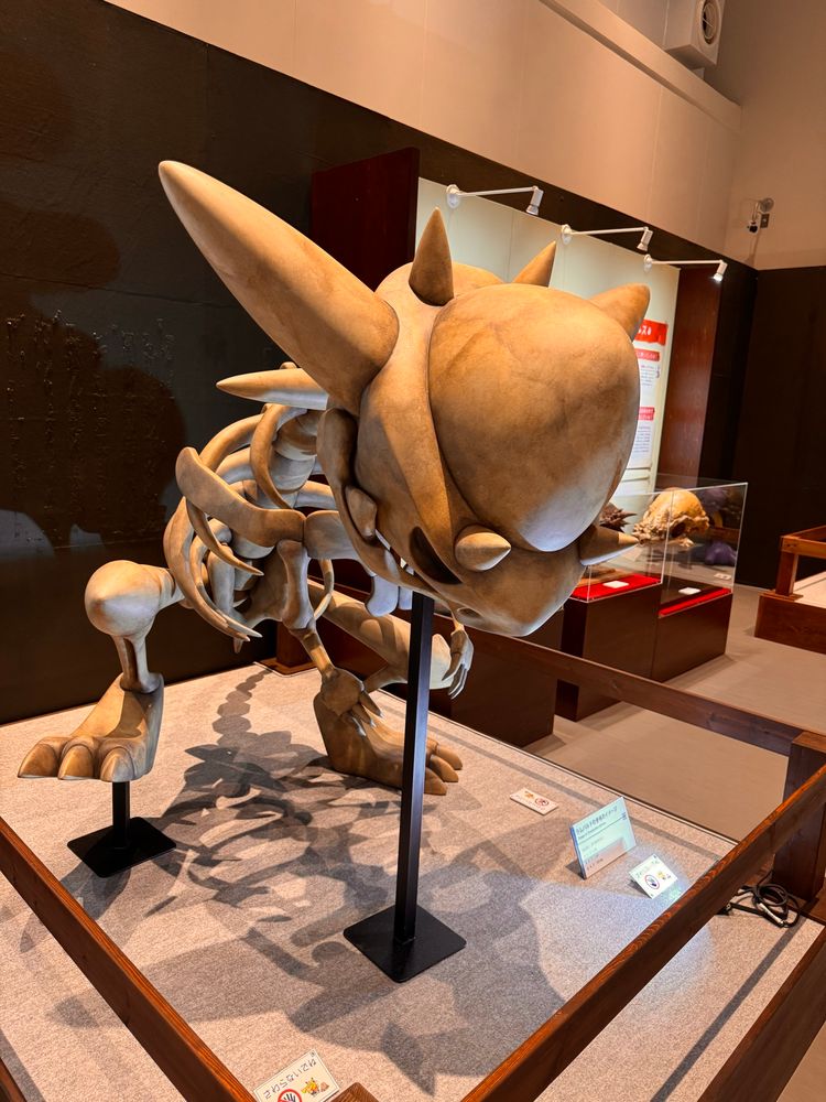 Replica fossil of the Pokémon Rampardos, with one leg raised in a stomping, rampaging fashion.
