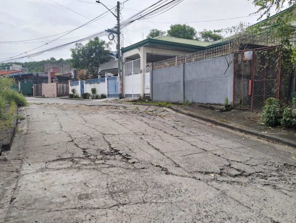An uneven paved road with multiple cracks