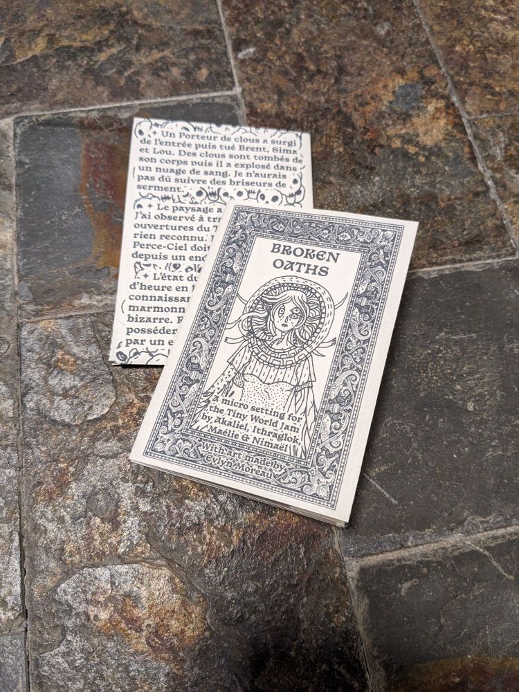 Photo du jeu Serments Brisés, un petit zine noir et blanc au format A7. Un dessin d'Evlyn Moreau en couverture représente une déesse avec trop d'yeux et un halo autour d'elle.