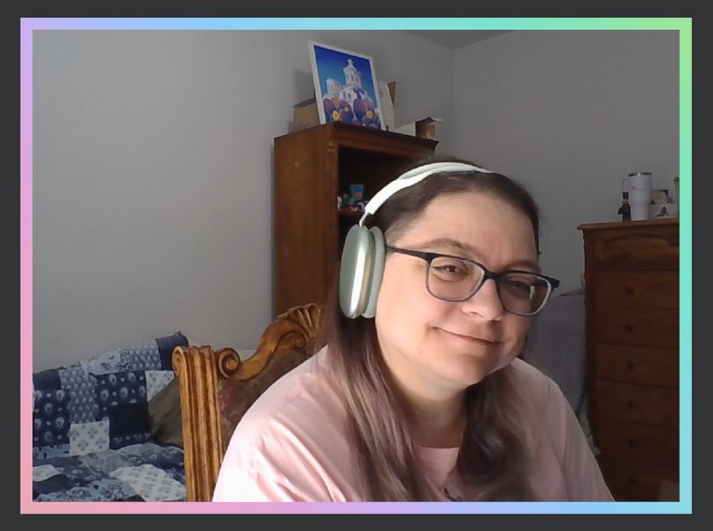 Me in my room ready to stream, in a pink tee and green headphones.