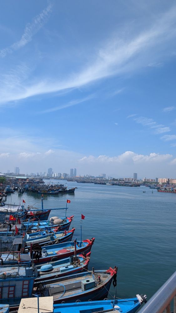 Da Nang skyscrapers in the distance with fishing boats at the front and a river between them