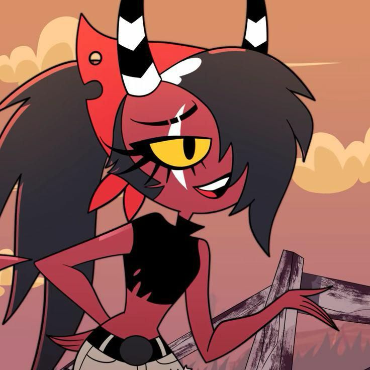 Sallie May in her classic fit - a black crop top and beige chaps with a red bandana tied around her head 