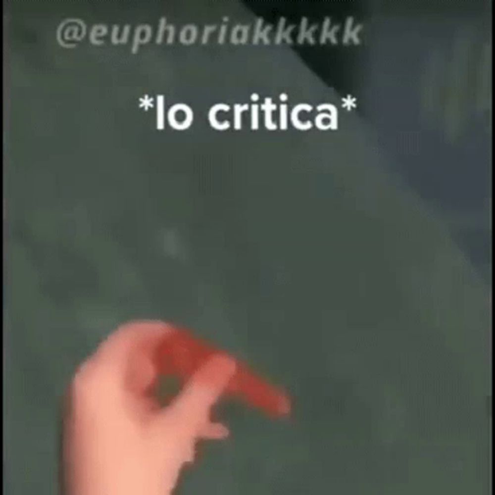 a person is holding a red object in their hand with the words `` lo critica '' written above it .