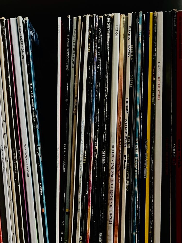 Vinyl albums on a shelf, mostly from The Cure discography.