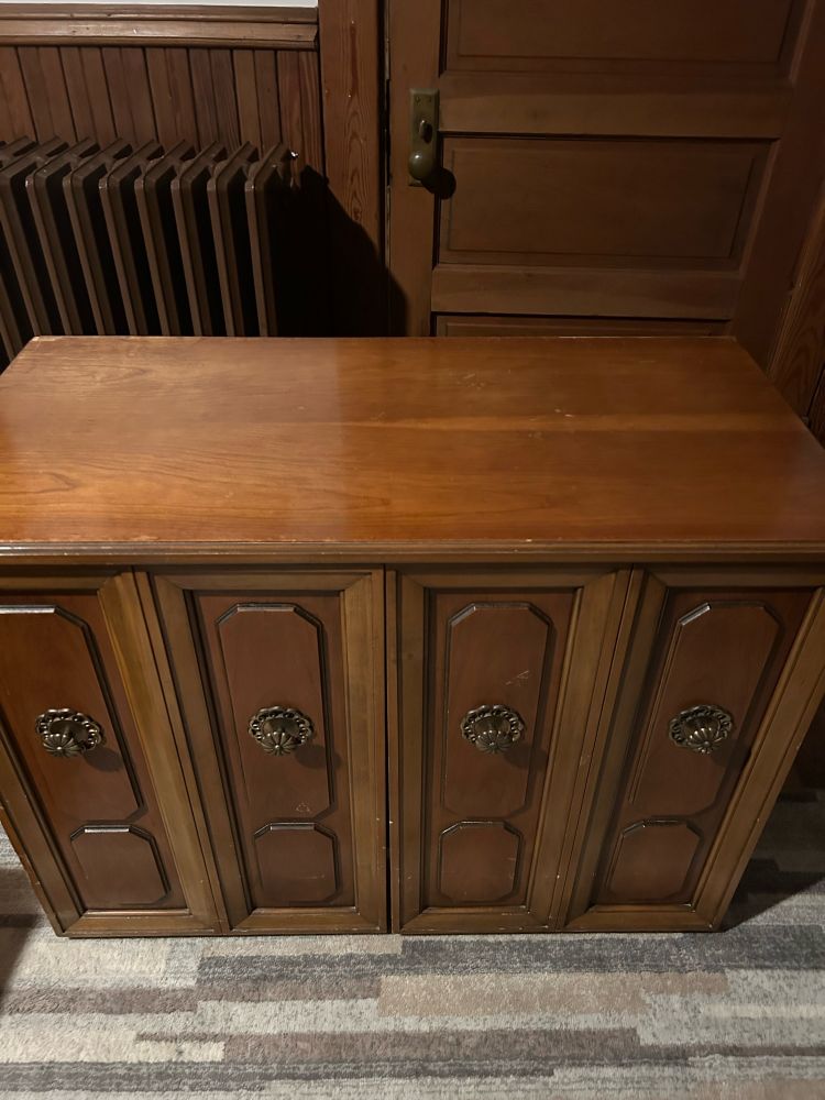 Closed wooden side board cabinet with bifold front doors bronze knobs.