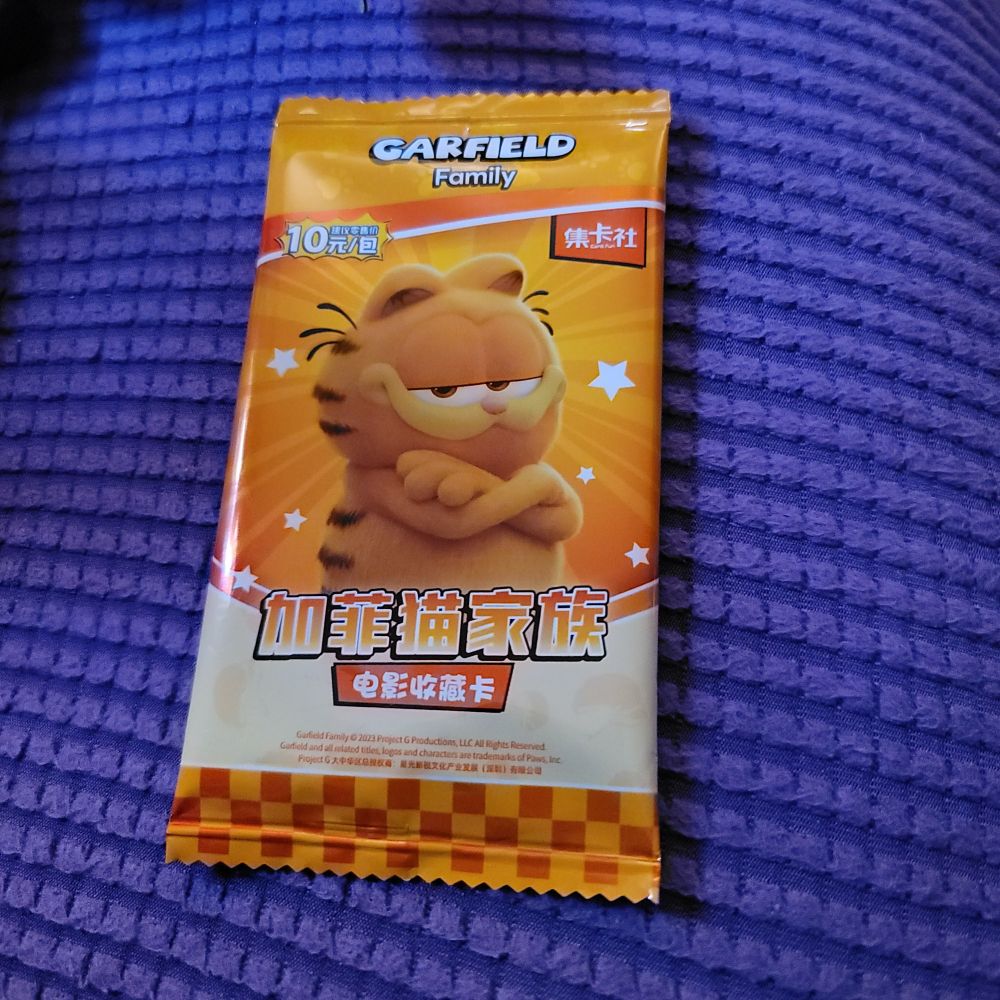 A foil wrapped Chinese booster pack of Garfield Family trading cards. Garfield the cat is on the front giving a smug look with his arms crossed.