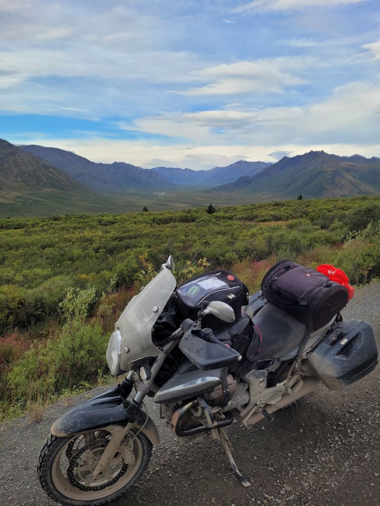 black moto guzzi motorcycle in foreground, arctic tundra in the summer in the background 