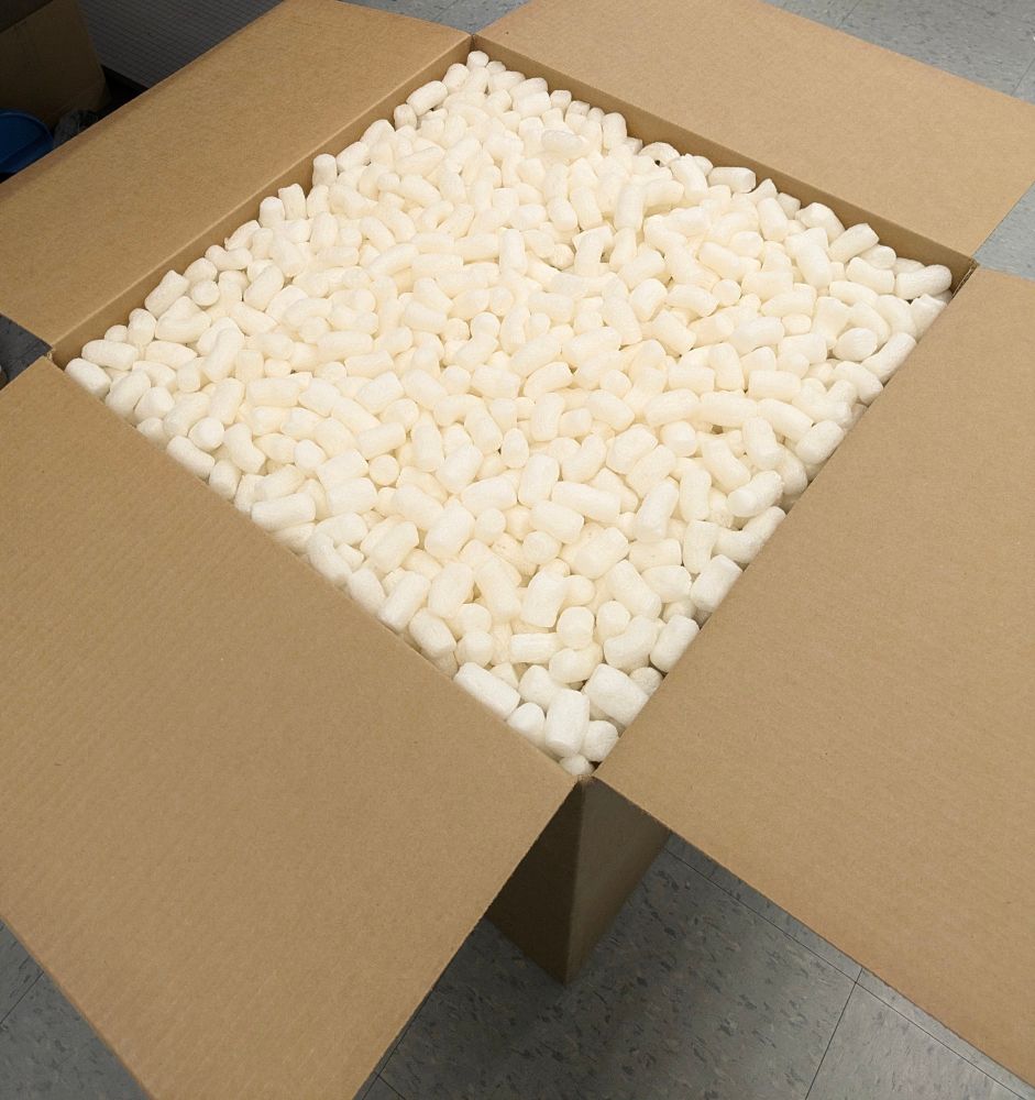 A cardboard box filled to the brim with plain white packing peanuts