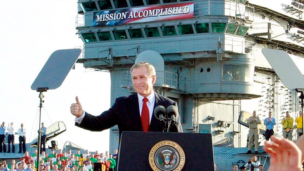 George W. Bush flashing a thumbs up behind a lectern with the presidential seal on it. Behind him is a large banner reading "mission accomplished." (This image ended up being pretty ironic because the mission was in no way accomplished, but George W. Bush gives no indication of anything but pure victory.)