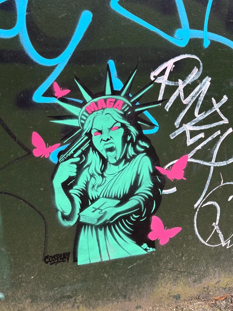 A graffiti of the Statue of Liberty. She has a the word MAGA on her crown and is holding a gun to her head. Found on a bridge in Worthing. 
