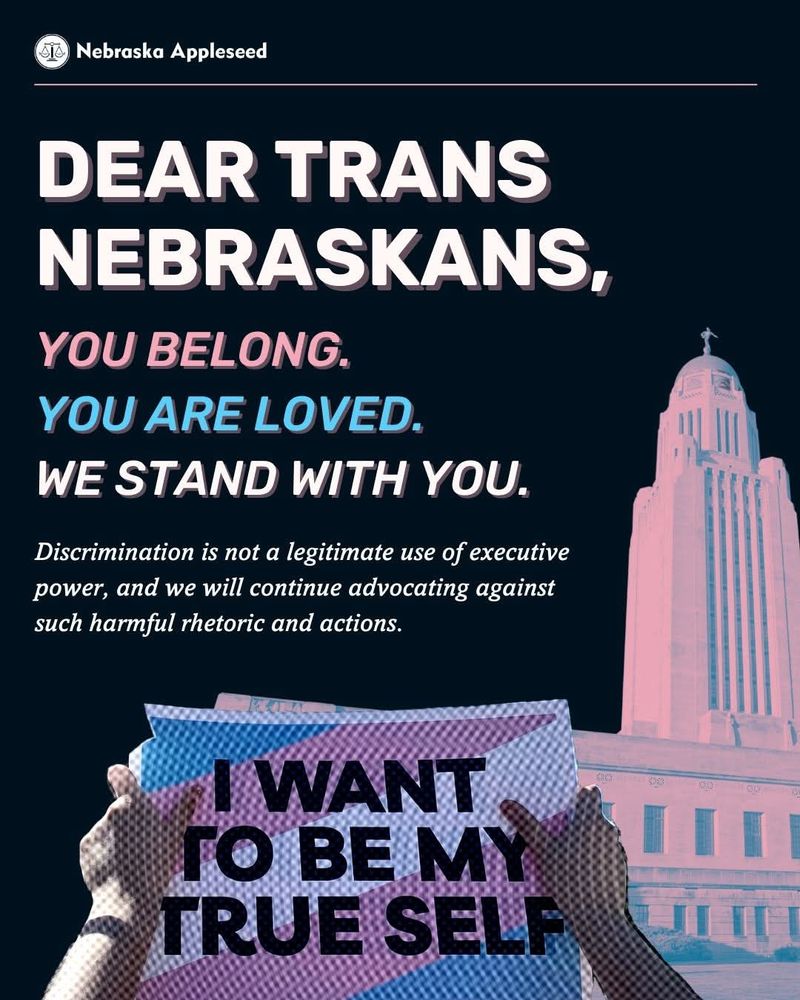 A piece of art from Nebraska Appleseed shows 2 hands holding a blue, pink, and white sign, reading: I WANT TO BE MY TRUE SELF. In the background is the Nebraska state capitol building. 
The top reads:
DEAR TRANS NEBRASKANS, 
YOU BELONG. YOU ARE LOVED. 
WE STAND WITH YOU. 
Discrimination is not a legitimate use of executive power, and we will continue advocating against such harmful rhetoric and actions. 

