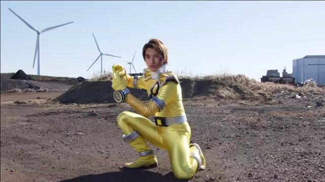 a man in a yellow superhero costume is kneeling in a dirt field