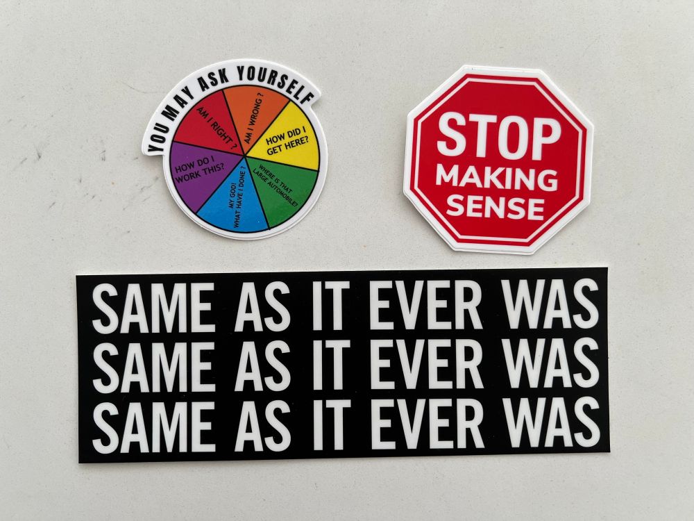 Three stickers referencing the Talking Heads. One in the shape of a stop sign reading “stop making sense” one reading “same as it ever was” over and over, and finally one in a Trivial Pursuit style design reading “you may ask yourself” followed by the lyrics to Once in a Lifetime.