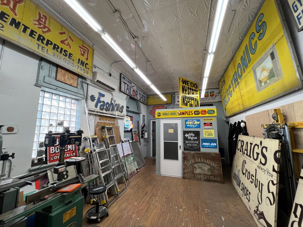 A photo of a workshop with many old yellow signs from closed businesses