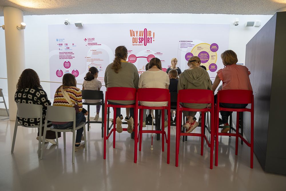 Des adolescents sont assis sur des chaises. Ils écoutent une animatrice leur donner des explications sur la saison 5 d'Xperium "Va y avoir du sport !".