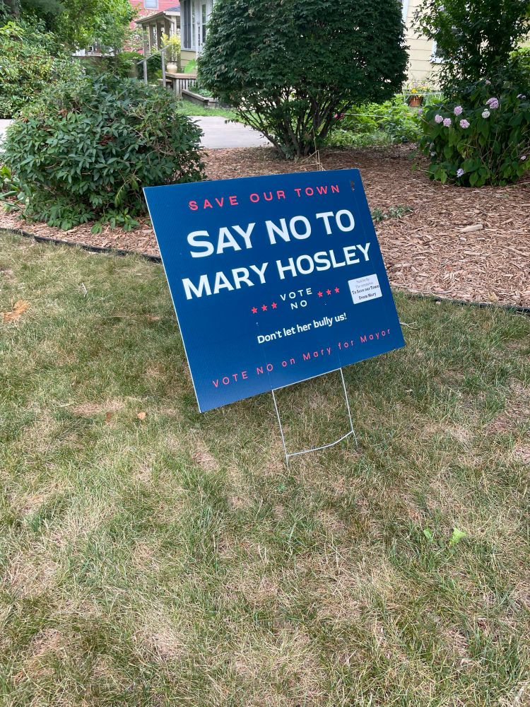 Campaign yard sign. It reads:
SAVE OUR TOWN
SAY NO TO MARY HOSLEY
VOTE NO
Don’t let her bully us!
VOTE NO on Mary for Mayor
Paid for by: the committee To Save Our Town From Mary