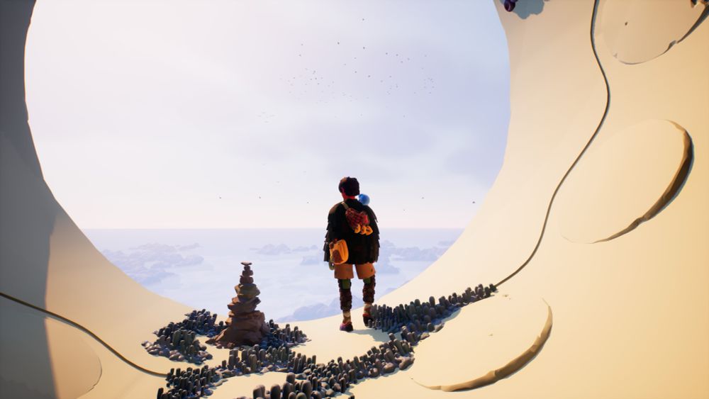 Une personne se tient à côté d’un monticule de pierre et regarde devant lui un panorama désert.