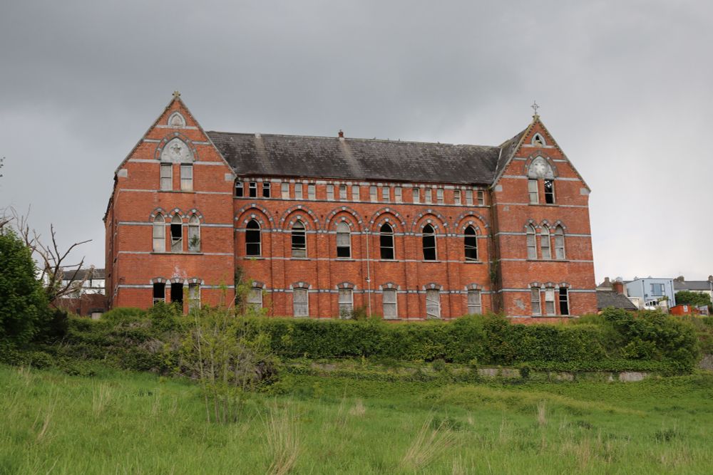 A photo of the former Magdalene Laundry at Sundays Well in Cork. It's a large red brick building on high ground.