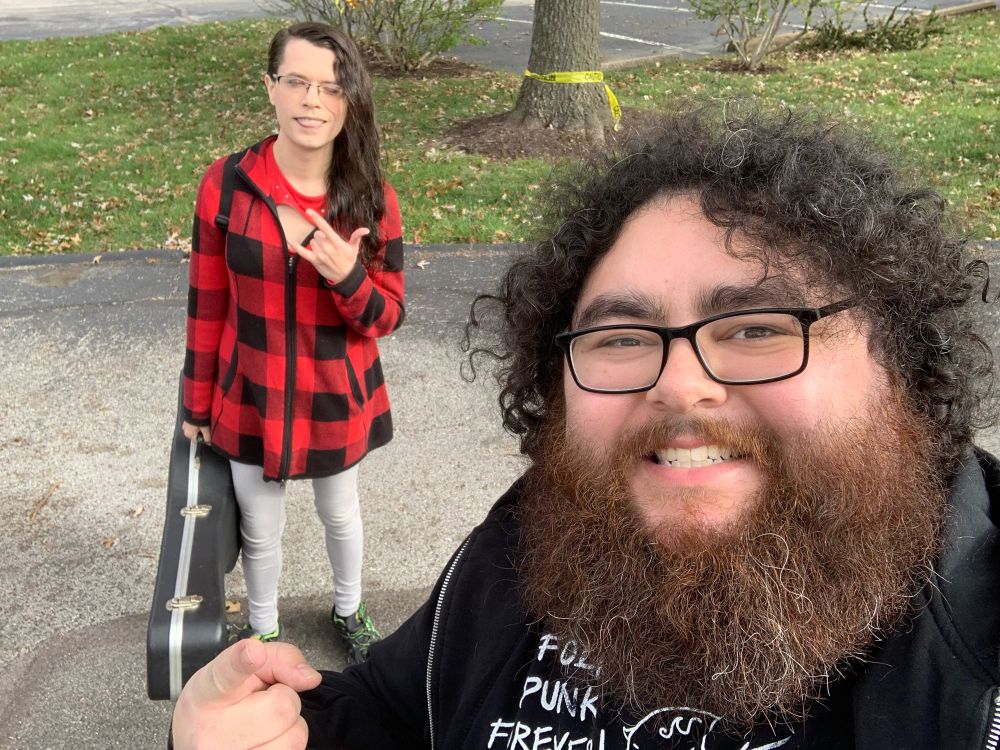 Janelle carrying her guitar case while Chris takes a selfie of them