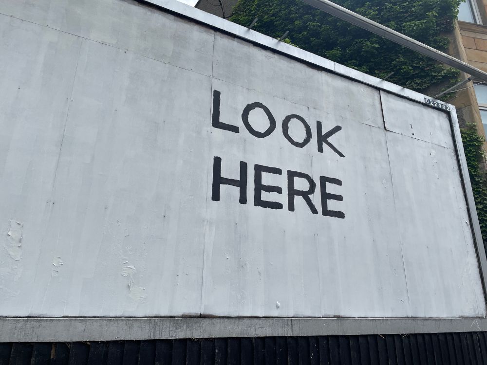 White billboard with black lettering saying look here