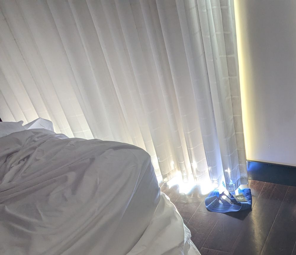 A crumpled blue jock strap on the floor next to the window where the shades are drawn.