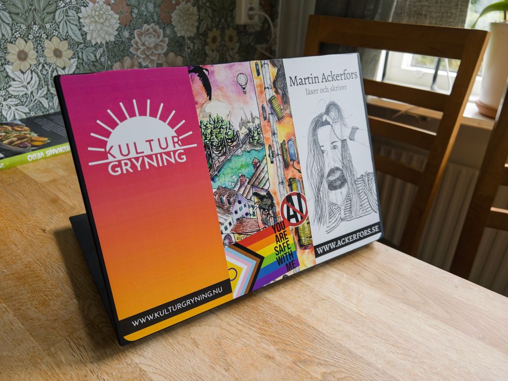 Laptop med klistermärke med Kulturgryning, Ackerfors.se, You Are Safe With Me, No AI och en akvarell. 